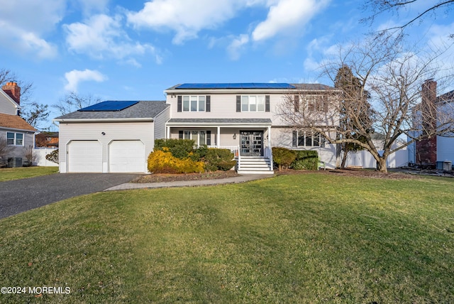 view of front property featuring a porch, solar panels, a front yard, and a garage