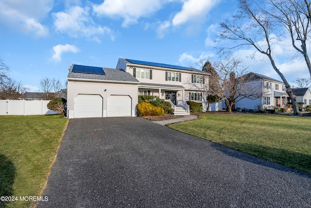 front facade with a front yard, covered porch, solar panels, and a garage