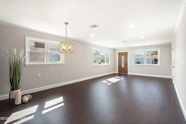 unfurnished living room featuring visible vents, crown molding, dark wood finished floors, baseboards, and a chandelier