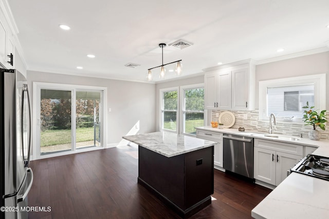 kitchen featuring decorative backsplash, crown molding, light stone countertops, white cabinets, and stainless steel appliances