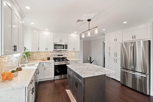 kitchen featuring dark wood-type flooring, white cabinetry, tasteful backsplash, a sink, and appliances with stainless steel finishes
