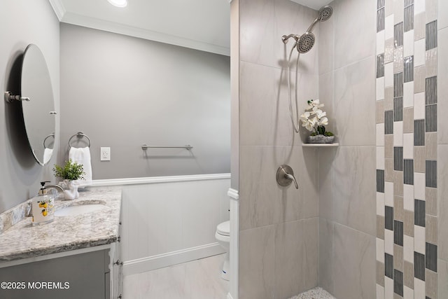 bathroom featuring vanity, wainscoting, toilet, and tiled shower