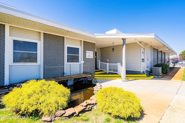 exterior space with brick siding, central air condition unit, and covered porch