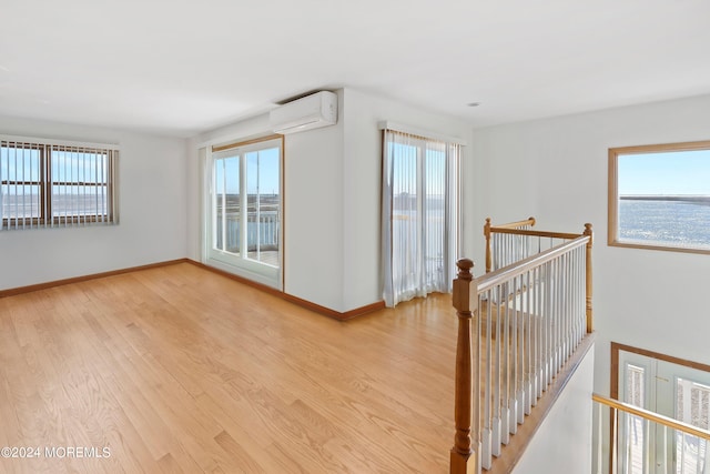 corridor with a healthy amount of sunlight, light hardwood / wood-style flooring, and a wall mounted AC