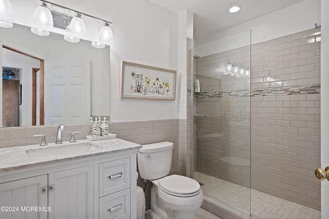 bathroom featuring an enclosed shower, oversized vanity, toilet, and tile walls