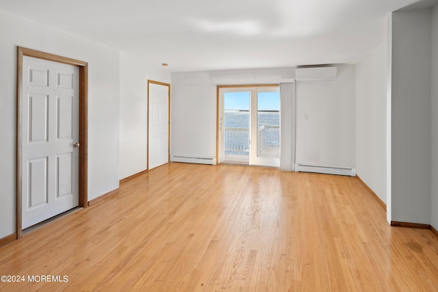 unfurnished room featuring a wall unit AC, light hardwood / wood-style floors, and a baseboard radiator