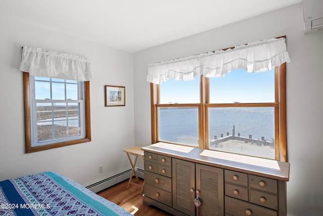 bedroom featuring a wall mounted AC, hardwood / wood-style floors, and a baseboard radiator