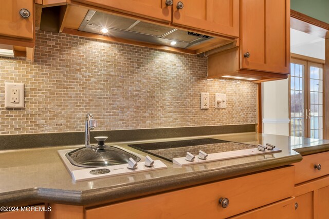 kitchen featuring stovetop, sink, and tasteful backsplash