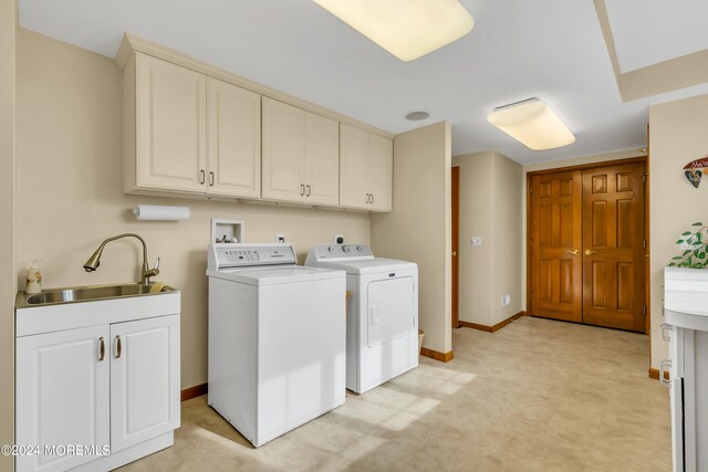 clothes washing area with cabinets, sink, and washer and clothes dryer