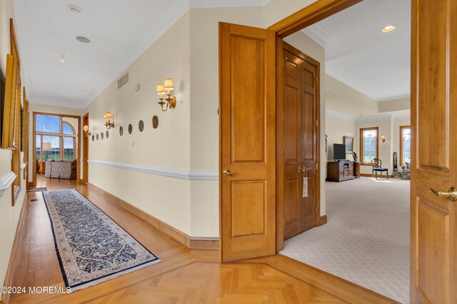 hall with crown molding, parquet floors, and plenty of natural light