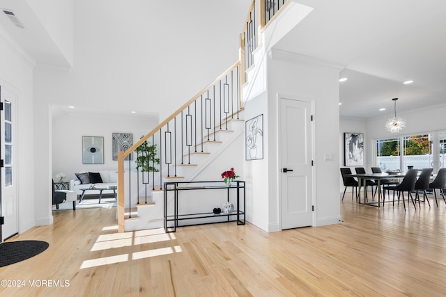 stairway with an inviting chandelier, hardwood / wood-style flooring, and ornamental molding