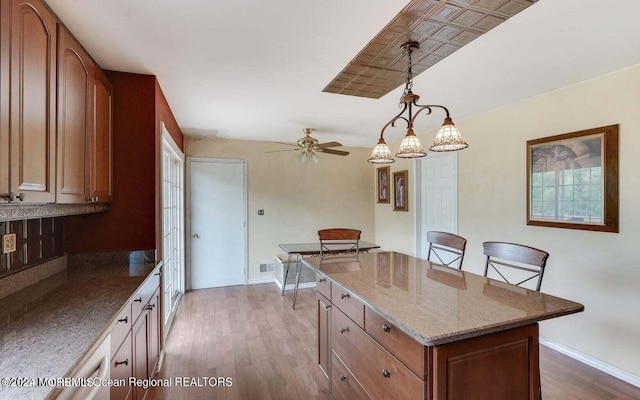 kitchen with a center island, pendant lighting, dark hardwood / wood-style floors, a kitchen bar, and ceiling fan