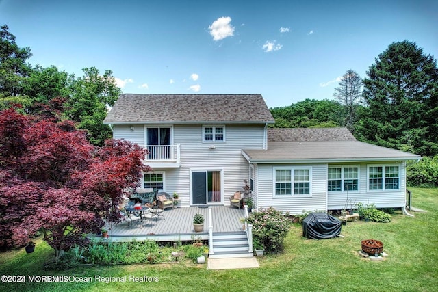 rear view of house with an outdoor fire pit, a yard, a balcony, and a deck