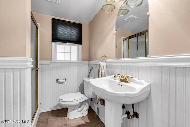 bathroom featuring tile patterned flooring, toilet, and an enclosed shower