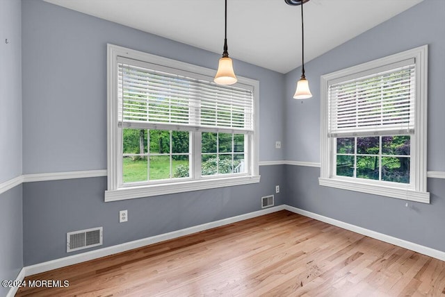 empty room with plenty of natural light, light wood-type flooring, and lofted ceiling