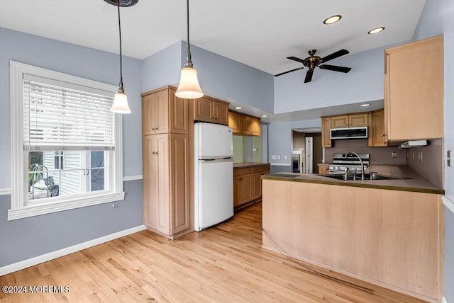 kitchen with light wood-type flooring, pendant lighting, white refrigerator, and a wealth of natural light