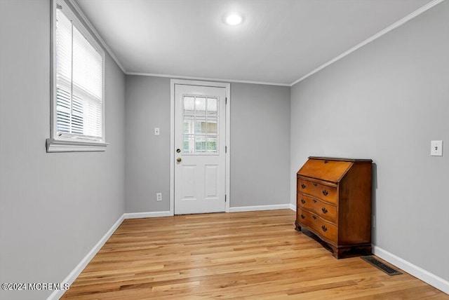 foyer with light wood-type flooring, plenty of natural light, and ornamental molding