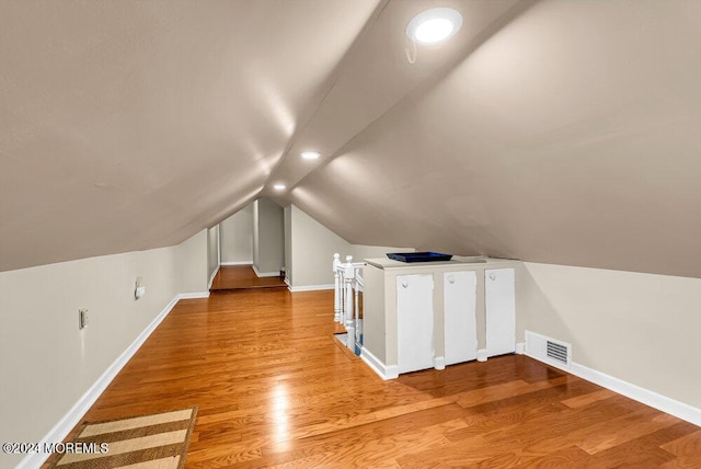 additional living space with wood-type flooring and vaulted ceiling