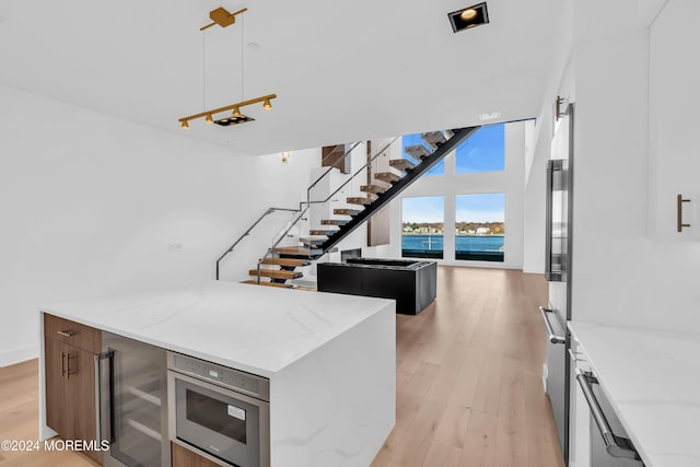 kitchen with light stone countertops, light wood-type flooring, a water view, and stainless steel appliances