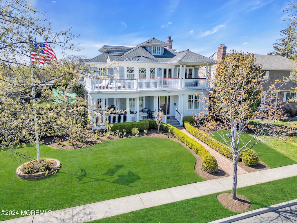 view of front of house with a balcony, covered porch, and a front yard