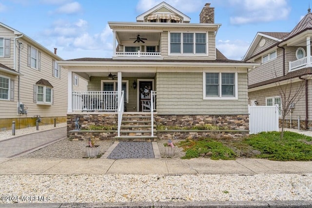 traditional style home featuring a chimney, a balcony, a porch, and a ceiling fan