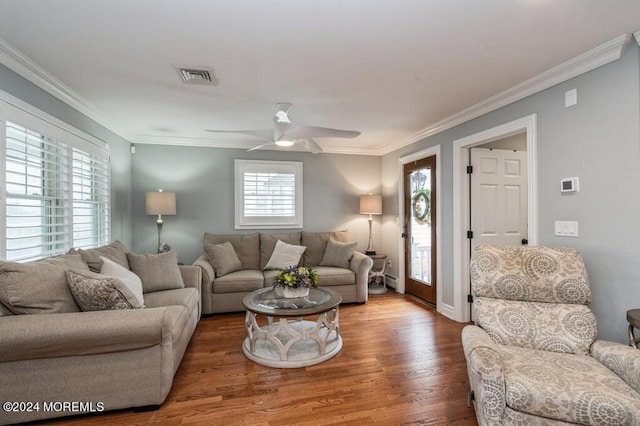 living room featuring visible vents, a ceiling fan, wood finished floors, crown molding, and baseboards