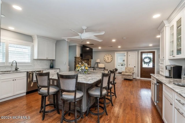 kitchen featuring a sink, stainless steel dishwasher, a breakfast bar, and white cabinets