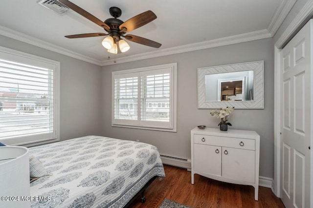 bedroom featuring dark wood-style floors, visible vents, multiple windows, and a baseboard heating unit