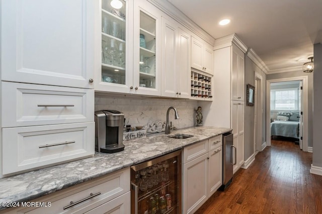 bar with backsplash, beverage cooler, dark wood finished floors, ornamental molding, and a sink