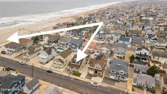 drone / aerial view featuring a residential view, a beach view, and a water view