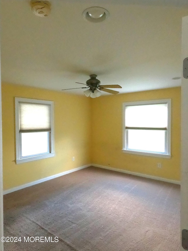 carpeted empty room with ceiling fan and a healthy amount of sunlight