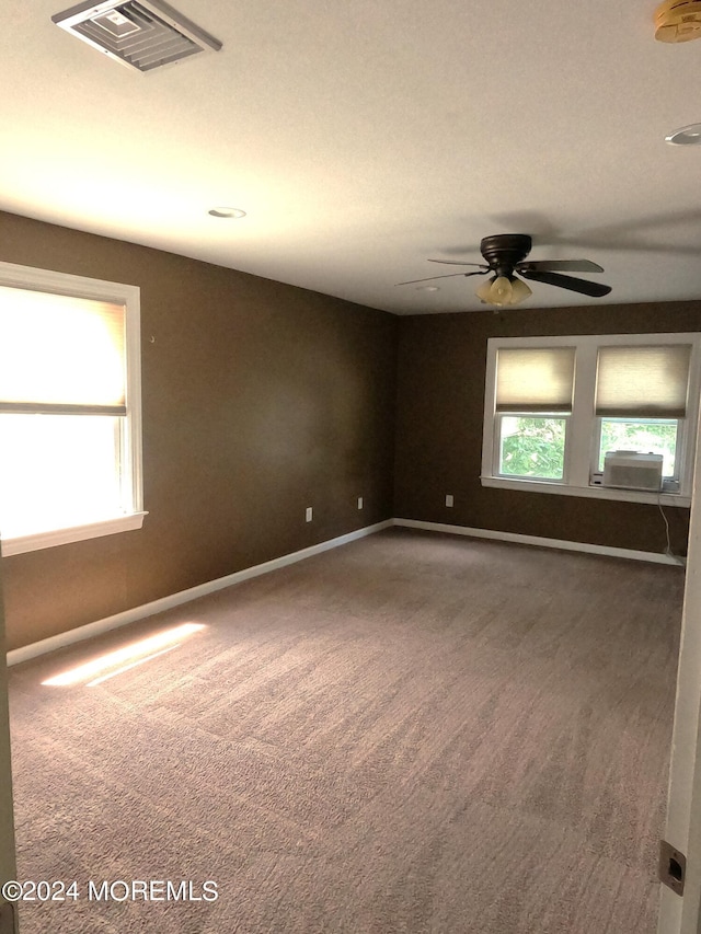 carpeted empty room featuring ceiling fan, cooling unit, and plenty of natural light