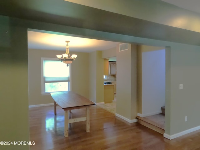 unfurnished dining area featuring a notable chandelier and light hardwood / wood-style floors