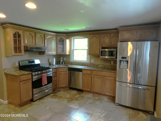 kitchen with stainless steel appliances, sink, light tile patterned flooring, light brown cabinets, and light stone counters