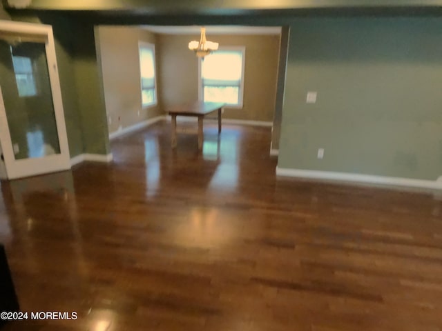 empty room with wood-type flooring and a chandelier