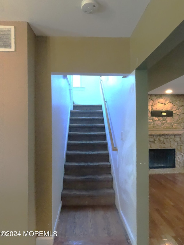 stairway with a fireplace and hardwood / wood-style floors