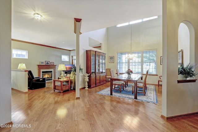 dining area with a healthy amount of sunlight, hardwood / wood-style flooring, crown molding, and a towering ceiling