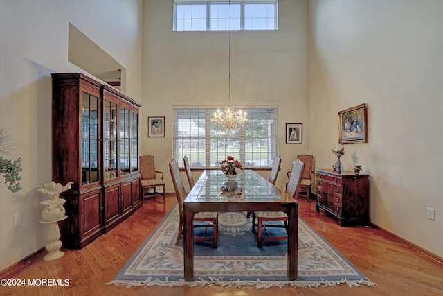 dining room featuring wood-type flooring, a notable chandelier, and a high ceiling