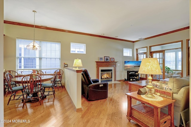 living room with ornamental molding, light hardwood / wood-style floors, and an inviting chandelier