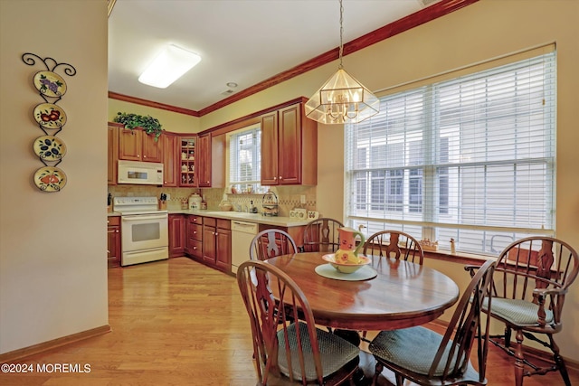 dining area featuring crown molding, a notable chandelier, and light wood-type flooring