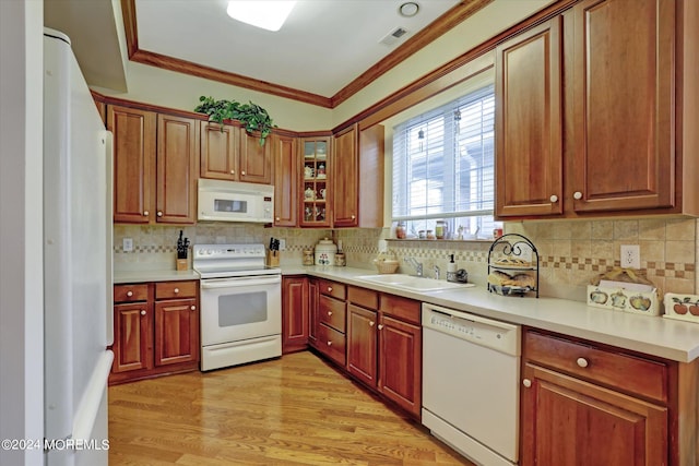 kitchen with sink, white appliances, tasteful backsplash, ornamental molding, and light hardwood / wood-style flooring