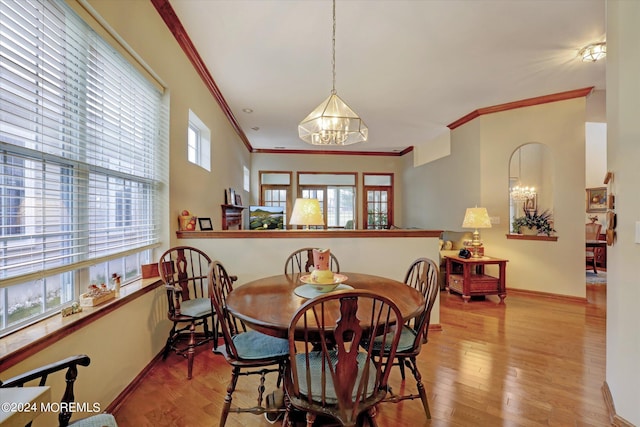 dining room with hardwood / wood-style flooring, crown molding, and a chandelier