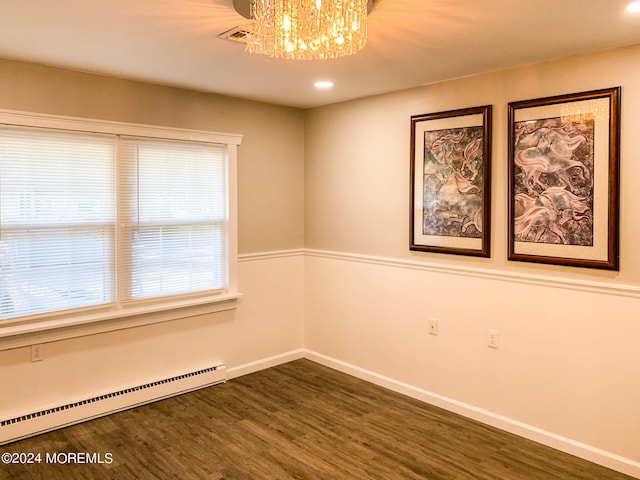 spare room with an inviting chandelier, a baseboard heating unit, and dark hardwood / wood-style flooring