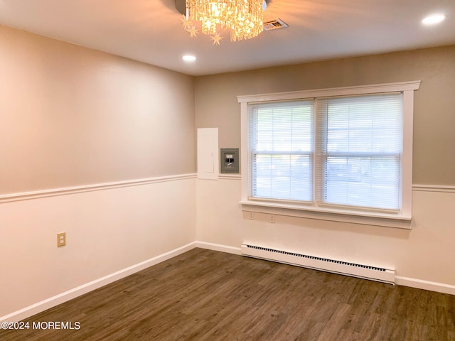 empty room featuring dark hardwood / wood-style floors, an inviting chandelier, and a baseboard heating unit