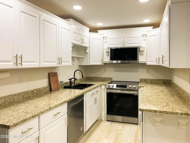 kitchen with appliances with stainless steel finishes, light hardwood / wood-style flooring, sink, and white cabinetry