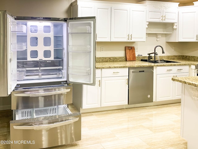 kitchen featuring light stone counters, sink, dishwasher, white cabinetry, and refrigerator