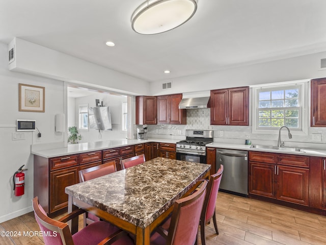 kitchen featuring sink, stainless steel appliances, wall chimney range hood, and tasteful backsplash