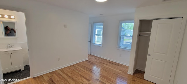 unfurnished bedroom featuring sink, a closet, and light wood-type flooring