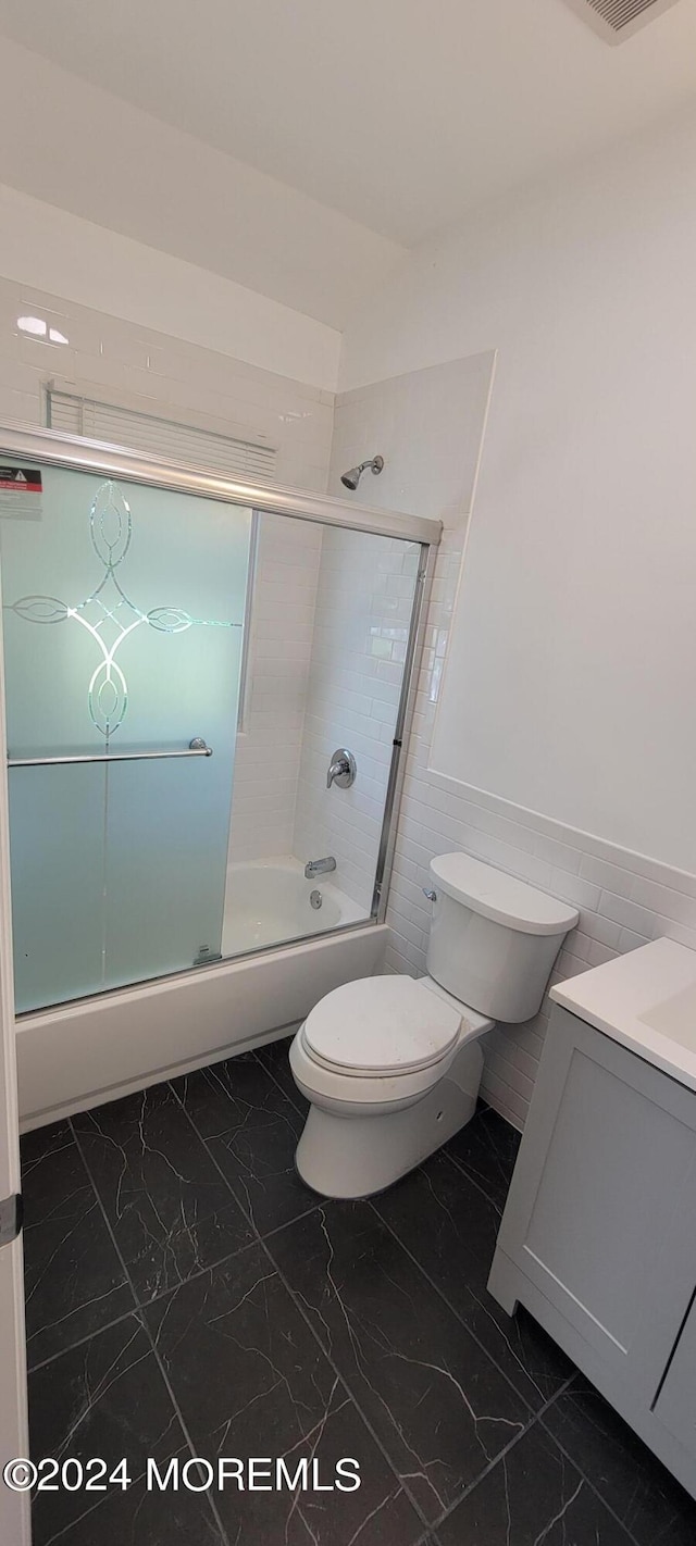 full bathroom featuring tile flooring, combined bath / shower with glass door, vanity, and toilet