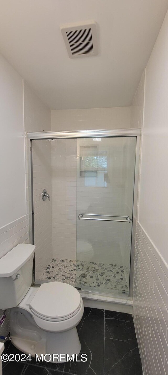 bathroom featuring tile flooring, walk in shower, tile walls, and toilet